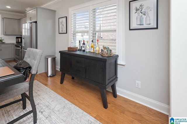 home office with ornamental molding and light hardwood / wood-style floors