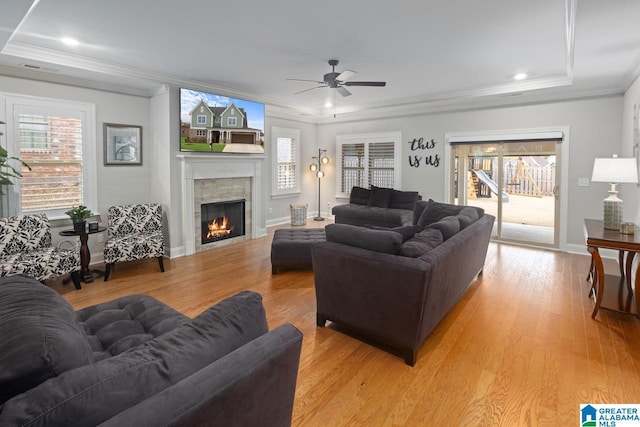 living room with ornamental molding, a tray ceiling, and light hardwood / wood-style flooring