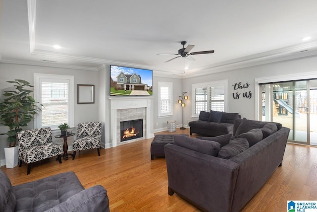 living room with a tile fireplace, wood-type flooring, a wealth of natural light, and crown molding