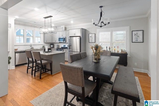 dining room featuring crown molding, sink, a notable chandelier, and light wood-type flooring