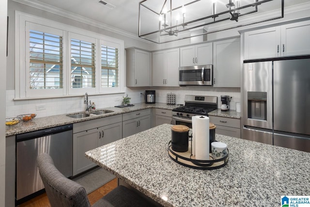 kitchen featuring sink, crown molding, appliances with stainless steel finishes, backsplash, and light stone counters