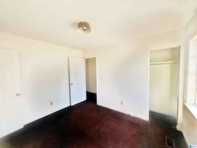 unfurnished bedroom with dark carpet and a closet