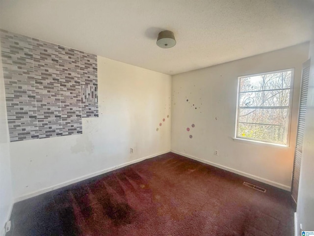 empty room with dark carpet and a textured ceiling