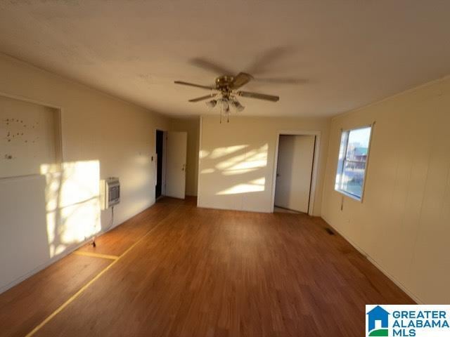 empty room with ceiling fan, wood finished floors, and heating unit