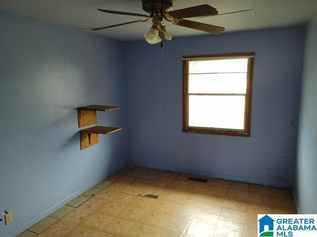 empty room featuring visible vents, ceiling fan, and baseboards