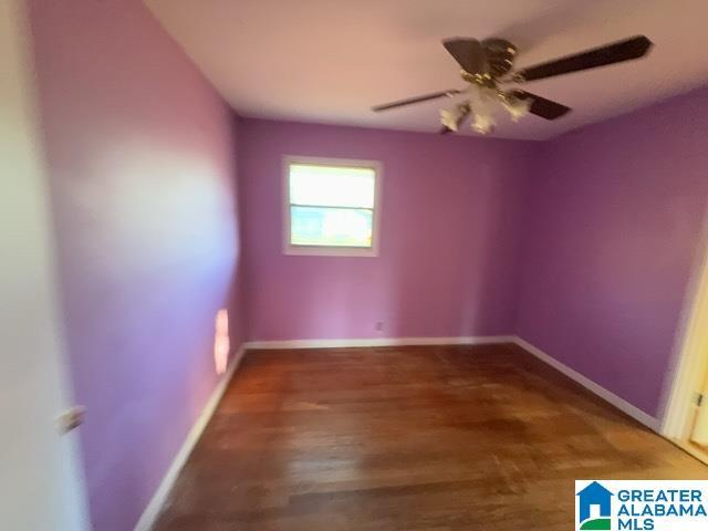 empty room with wood finished floors, a ceiling fan, and baseboards