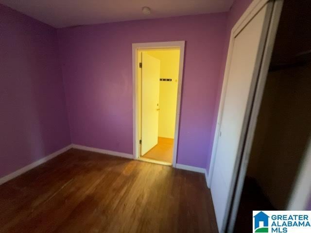 unfurnished bedroom with a closet, wood finished floors, and baseboards