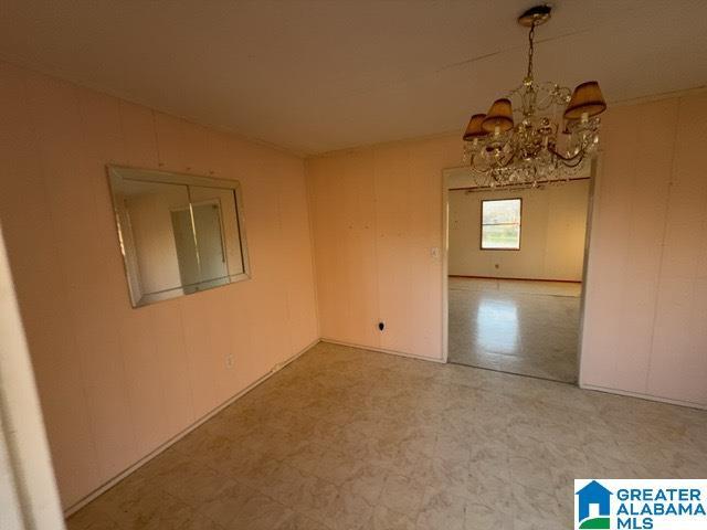 empty room with a notable chandelier and tile patterned floors