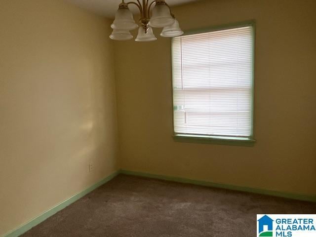 carpeted empty room featuring a chandelier