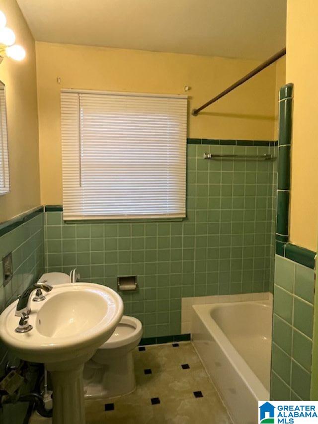 bathroom featuring tile patterned flooring, tile walls, and toilet