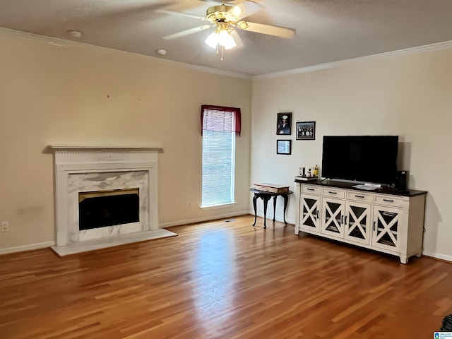 living room with ceiling fan, ornamental molding, hardwood / wood-style floors, and a high end fireplace