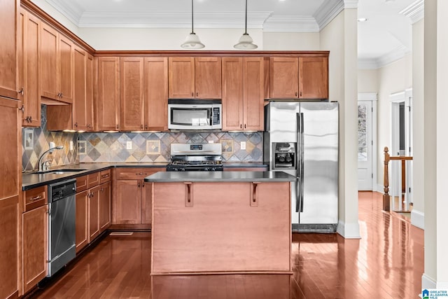 kitchen with sink, crown molding, decorative light fixtures, a center island, and stainless steel appliances