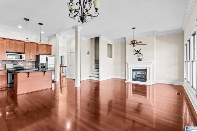 kitchen featuring pendant lighting, ceiling fan, backsplash, stainless steel appliances, and a kitchen bar