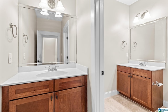 bathroom with a sink, baseboards, two vanities, and tile patterned flooring