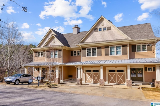 view of front of house featuring a porch, metal roof, a garage, driveway, and a standing seam roof