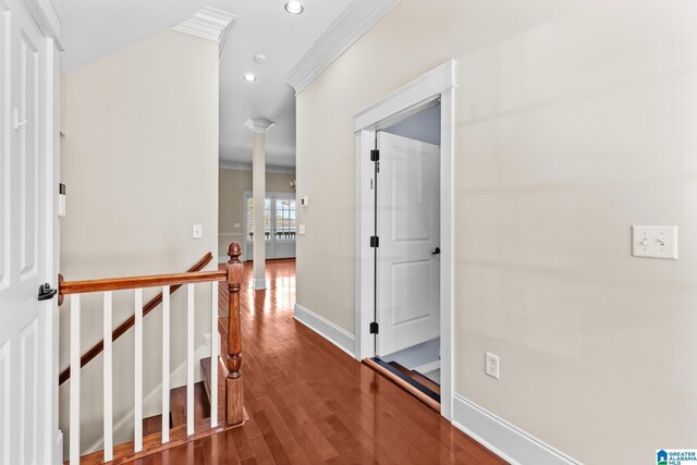 corridor with wood finished floors, ornate columns, recessed lighting, ornamental molding, and an upstairs landing