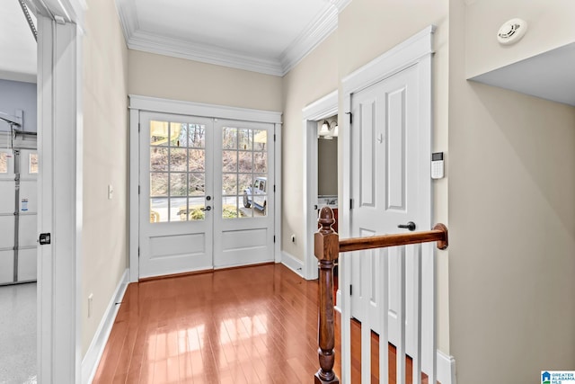 doorway to outside featuring french doors, baseboards, ornamental molding, and light wood finished floors