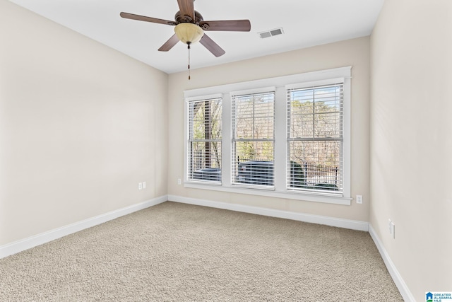 carpeted spare room featuring visible vents, baseboards, and a ceiling fan