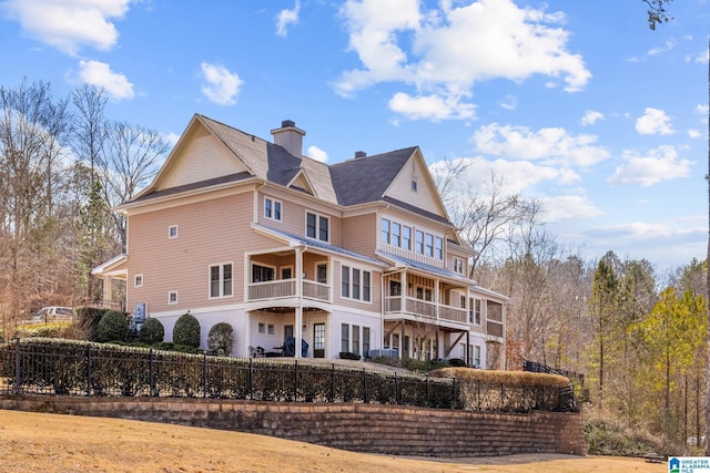 rear view of house with a fenced front yard and a chimney