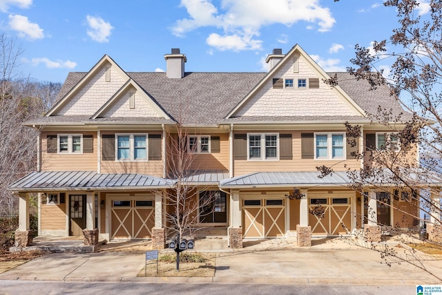 view of front of house with an attached garage, a porch, metal roof, driveway, and a standing seam roof