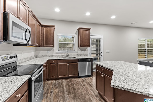 kitchen featuring dark hardwood / wood-style floors, sink, stainless steel appliances, light stone countertops, and dark brown cabinets