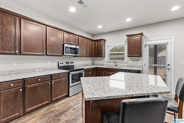 kitchen with dark brown cabinetry, sink, stainless steel appliances, and a kitchen breakfast bar