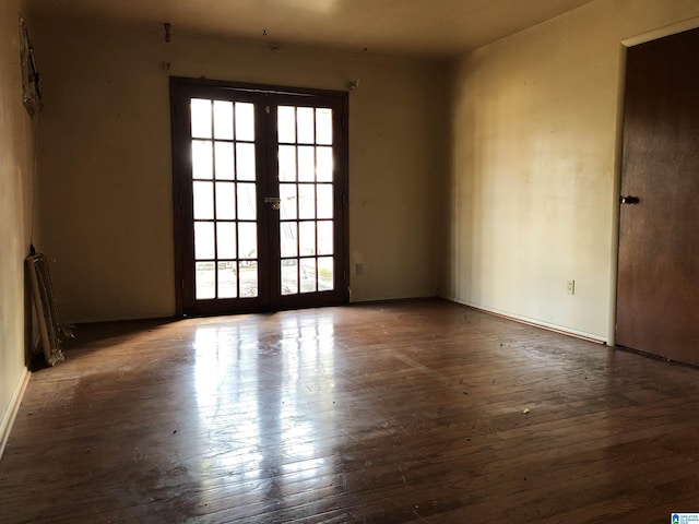 spare room featuring french doors and dark wood-type flooring