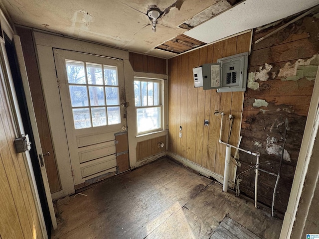 doorway to outside with electric panel and wood walls