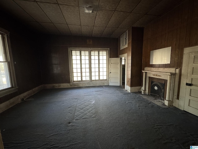 unfurnished living room with carpet flooring and wooden walls