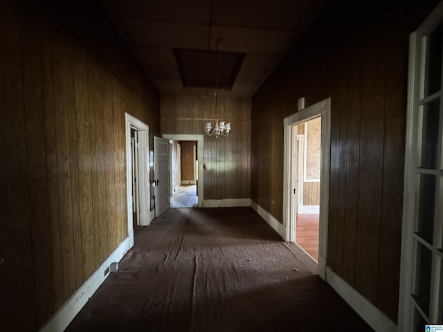 corridor featuring a chandelier and wooden walls