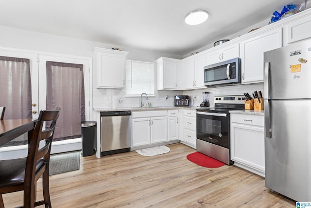 kitchen featuring stainless steel appliances, sink, white cabinets, and light hardwood / wood-style floors