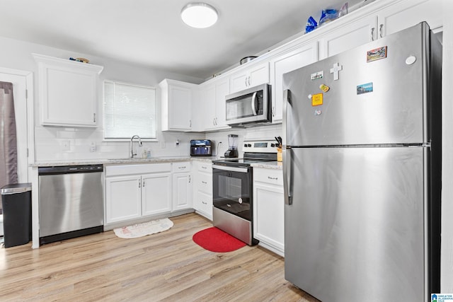 kitchen featuring sink, light hardwood / wood-style flooring, stainless steel appliances, decorative backsplash, and white cabinets