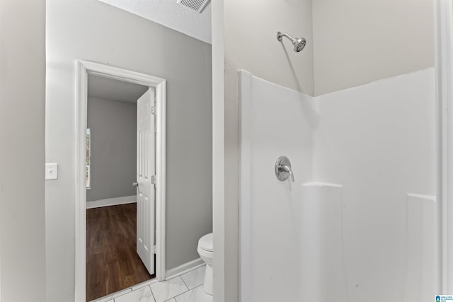 bathroom featuring a textured ceiling, toilet, and a shower