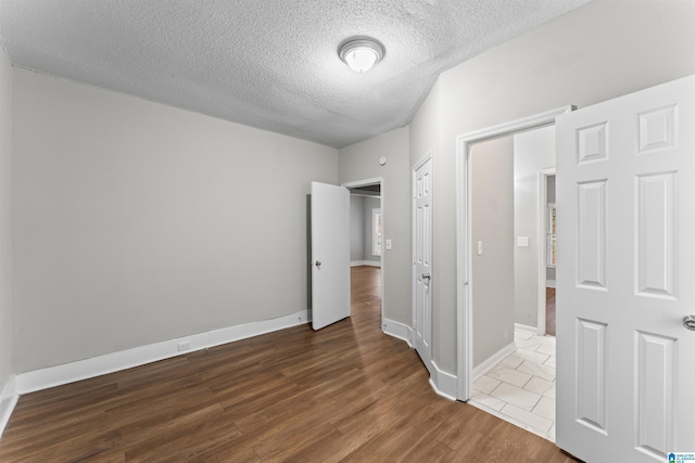 unfurnished bedroom with dark wood-type flooring and a textured ceiling