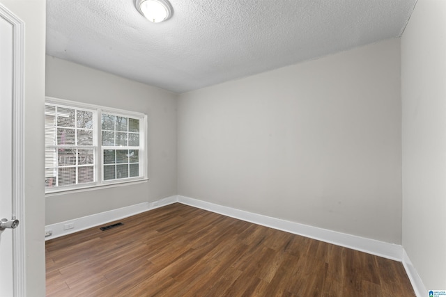 unfurnished room featuring dark wood-type flooring and a textured ceiling