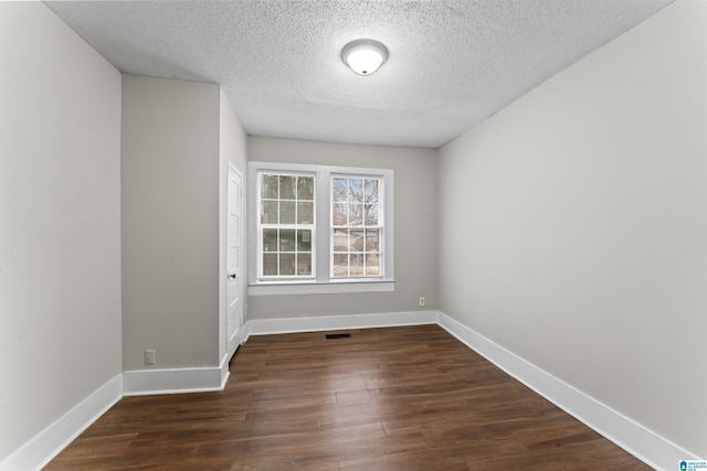 unfurnished room featuring dark wood-type flooring and a textured ceiling