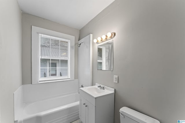 bathroom featuring vanity, a tub to relax in, and toilet