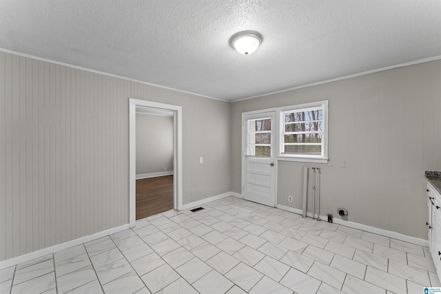 empty room with crown molding and a textured ceiling