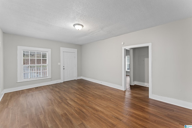 empty room featuring a textured ceiling and dark hardwood / wood-style flooring