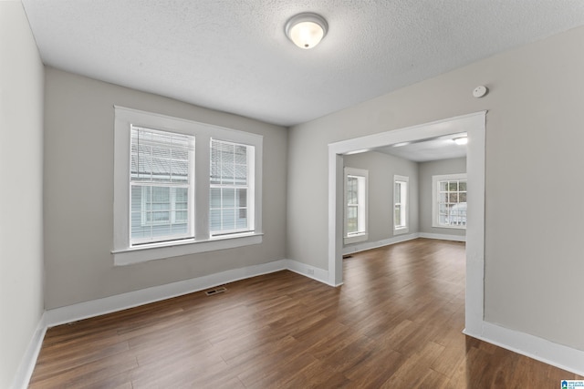 spare room featuring dark wood-type flooring and a textured ceiling