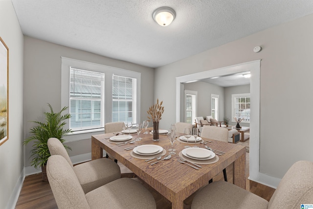 dining space with dark wood-type flooring, a textured ceiling, and a wealth of natural light