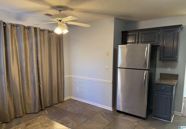 kitchen with stainless steel refrigerator, ceiling fan, and a textured ceiling