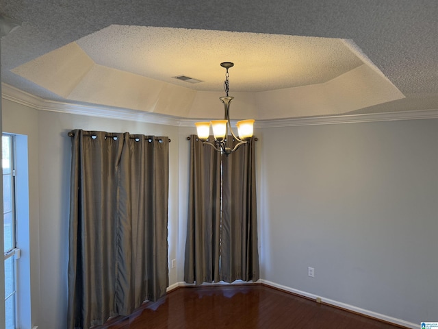 unfurnished room featuring hardwood / wood-style floors, a notable chandelier, a raised ceiling, crown molding, and a textured ceiling