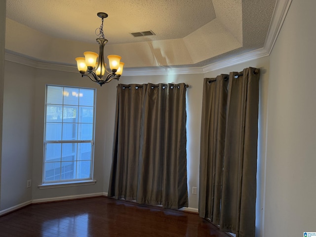 empty room featuring a chandelier, a tray ceiling, dark hardwood / wood-style flooring, and crown molding