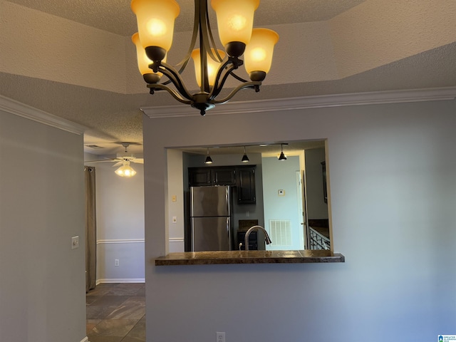 kitchen with crown molding, stainless steel refrigerator, a textured ceiling, decorative light fixtures, and kitchen peninsula