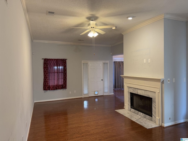 unfurnished living room featuring crown molding, ceiling fan, wood-type flooring, and a tiled fireplace