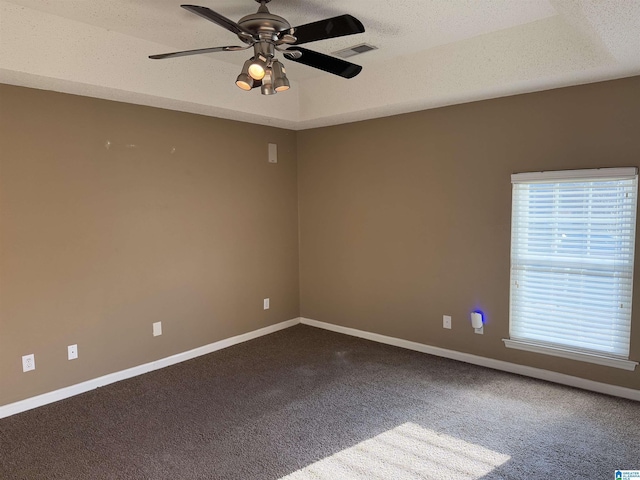 carpeted spare room featuring ceiling fan, a textured ceiling, and a tray ceiling