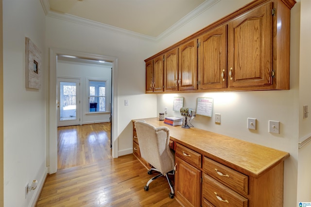 office space with ornamental molding, built in desk, and light hardwood / wood-style flooring