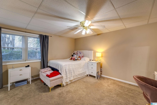 carpeted bedroom featuring ceiling fan and a drop ceiling