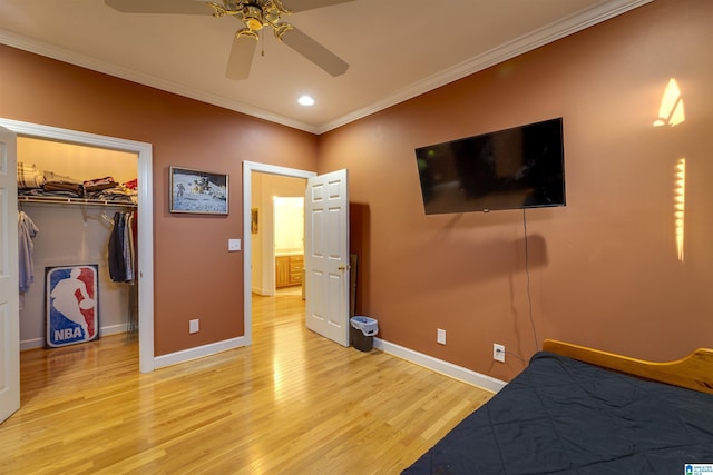 bedroom with ornamental molding, a spacious closet, light wood-type flooring, and a closet